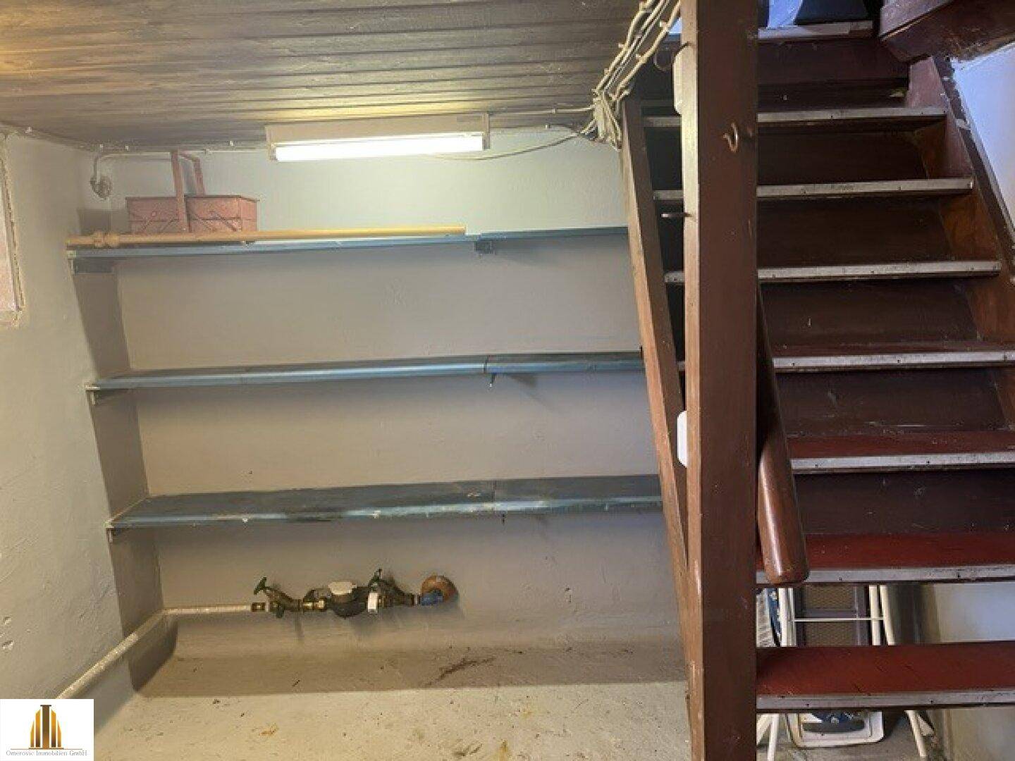Kellerraum mit Regalen und Holztreppe, ideal als Abstellraum nutzbar.