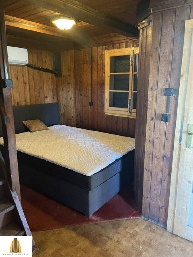 Schlafzimmer mit Holzwänden, Doppelbett und Klimaanlage in rustikalem Stil.