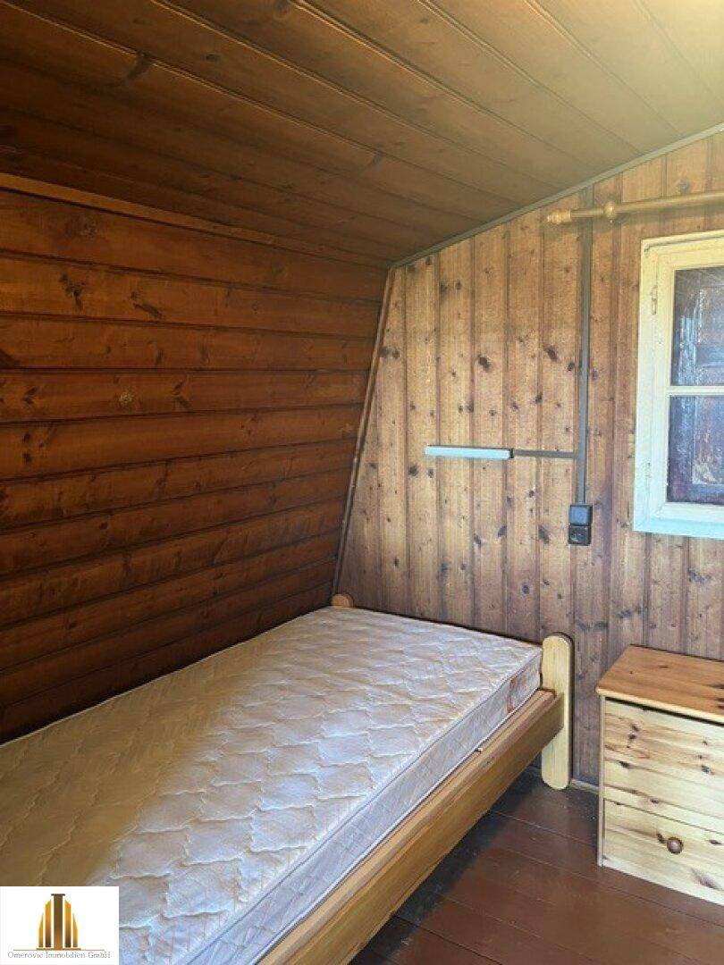 Gemütliches Schlafzimmer im Dachgeschoss mit Holzwänden und Einzelbett.