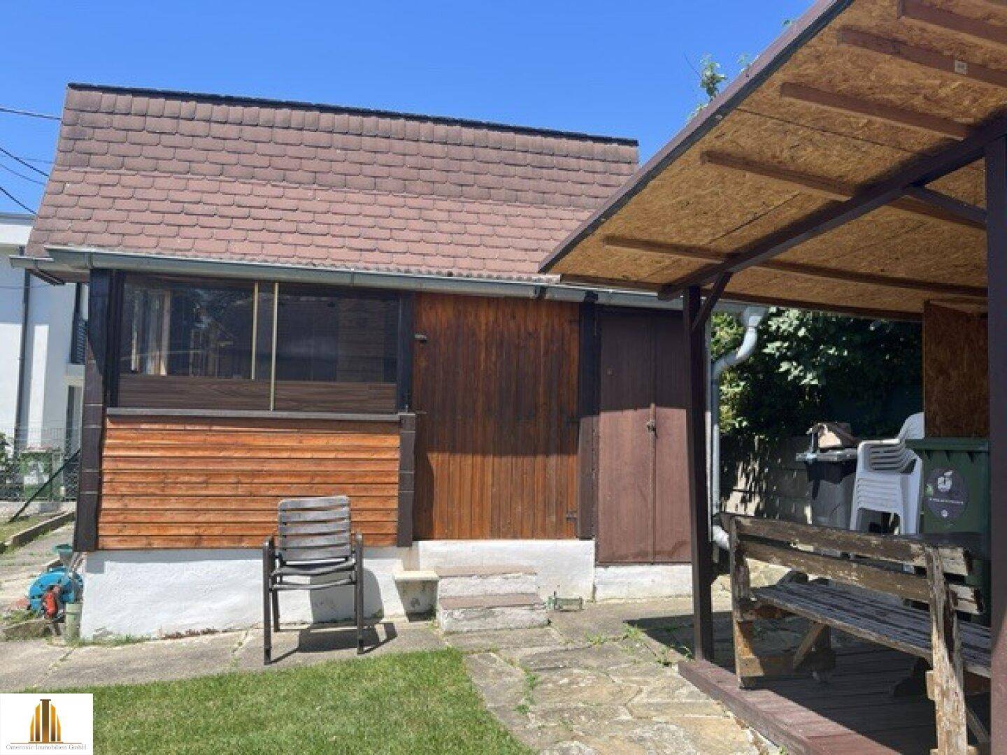 Seitenansicht des Holzhauses mit einem überdachten Bereich und Zugang zum Garten.