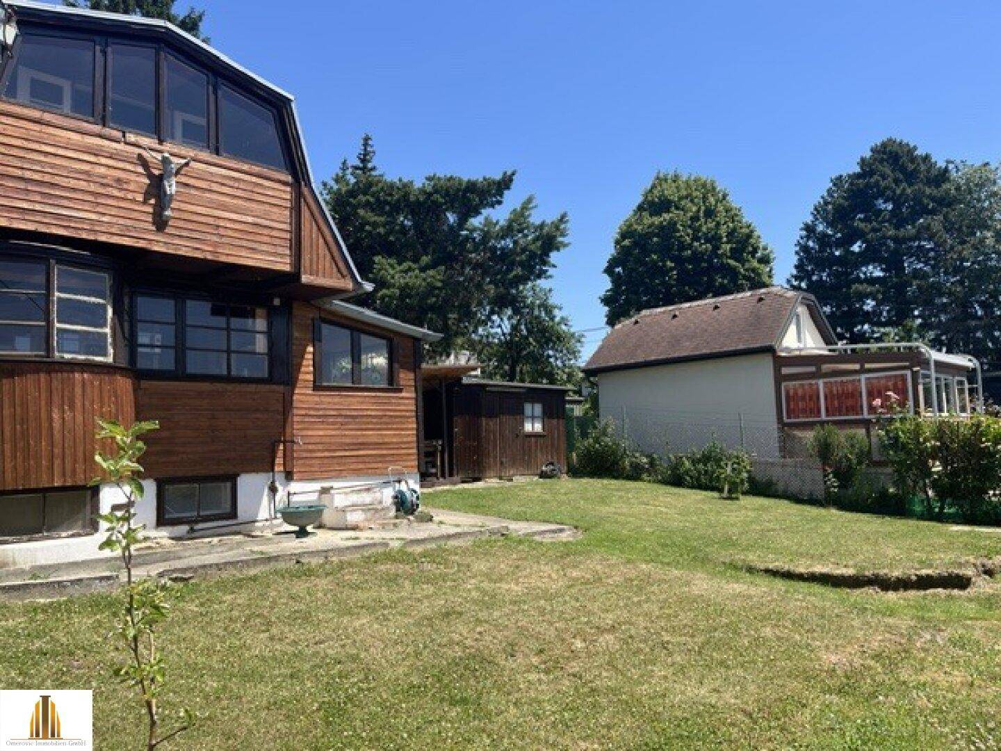 Gesamtansicht des Holzhauses mit großem Garten und angrenzendem Nachbargebäude.