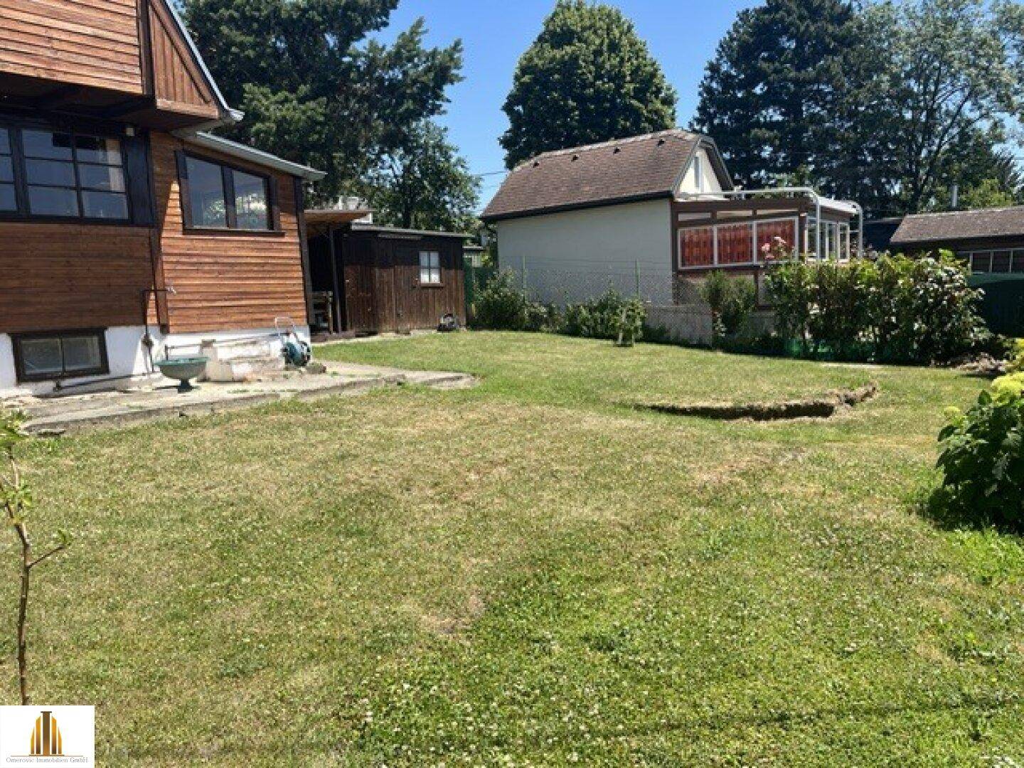 Großer Garten mit Rasenfläche und Blick auf das Holzhaus und die Umgebung.