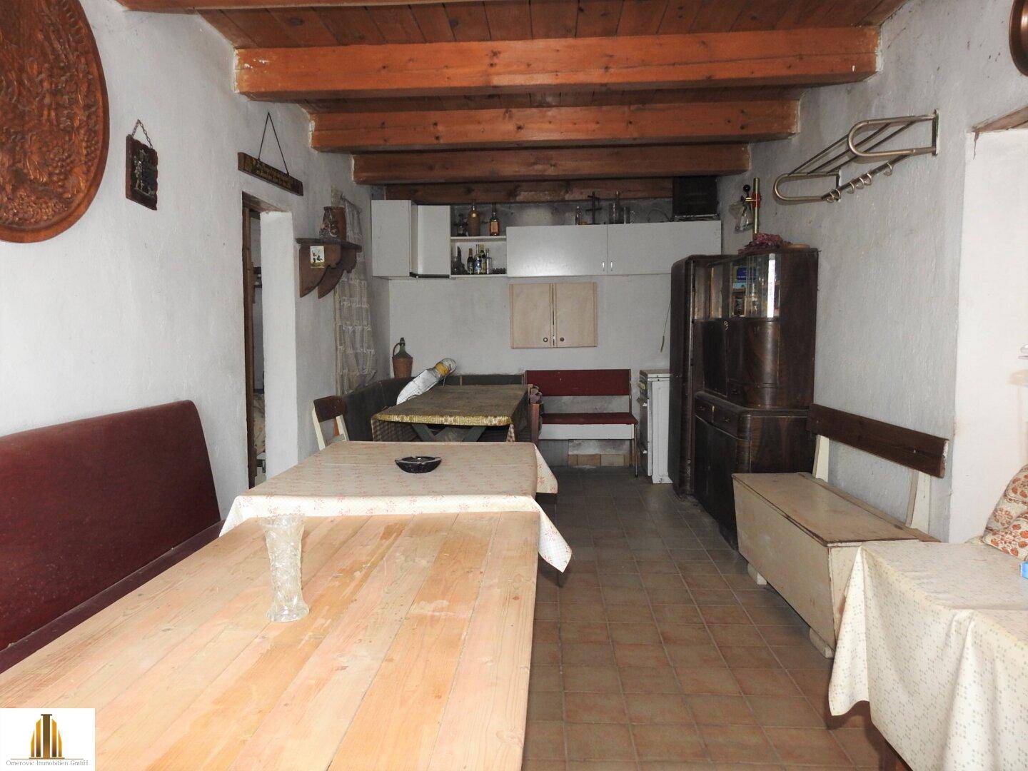 Gemütlicher Wohn-Essbereich mit Holzbalkendecke, gefliestem Boden und traditionellen Möbeln.