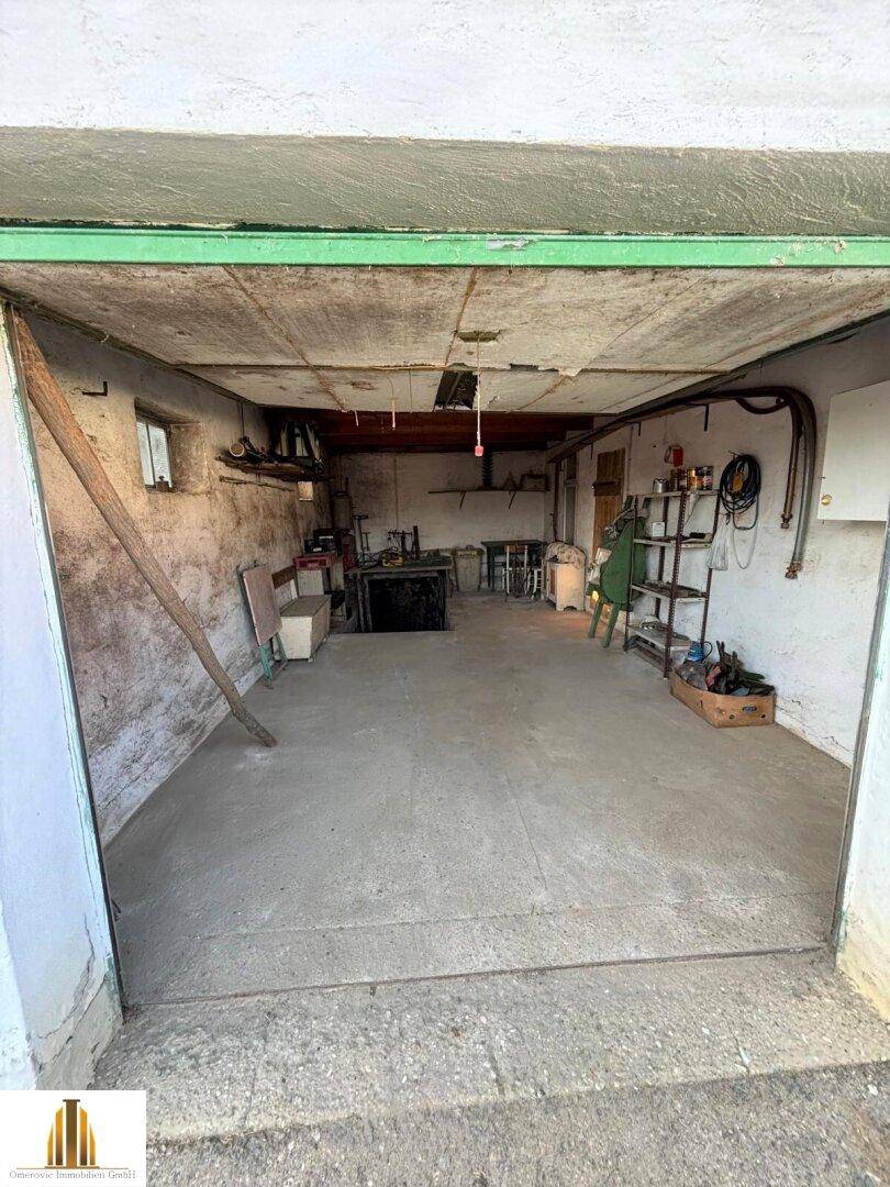 Geräumige Garage mit Betonboden, einfachen Wänden und Blick auf den Außenbereich.
