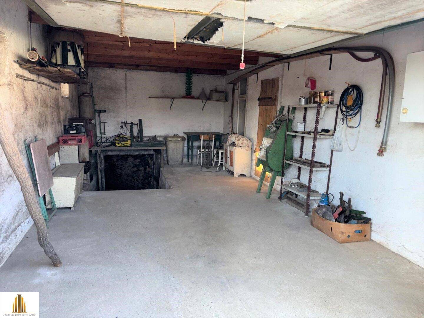 Einfache Garage mit Betonboden, Werkzeugen und einer Grube für Fahrzeugwartung.