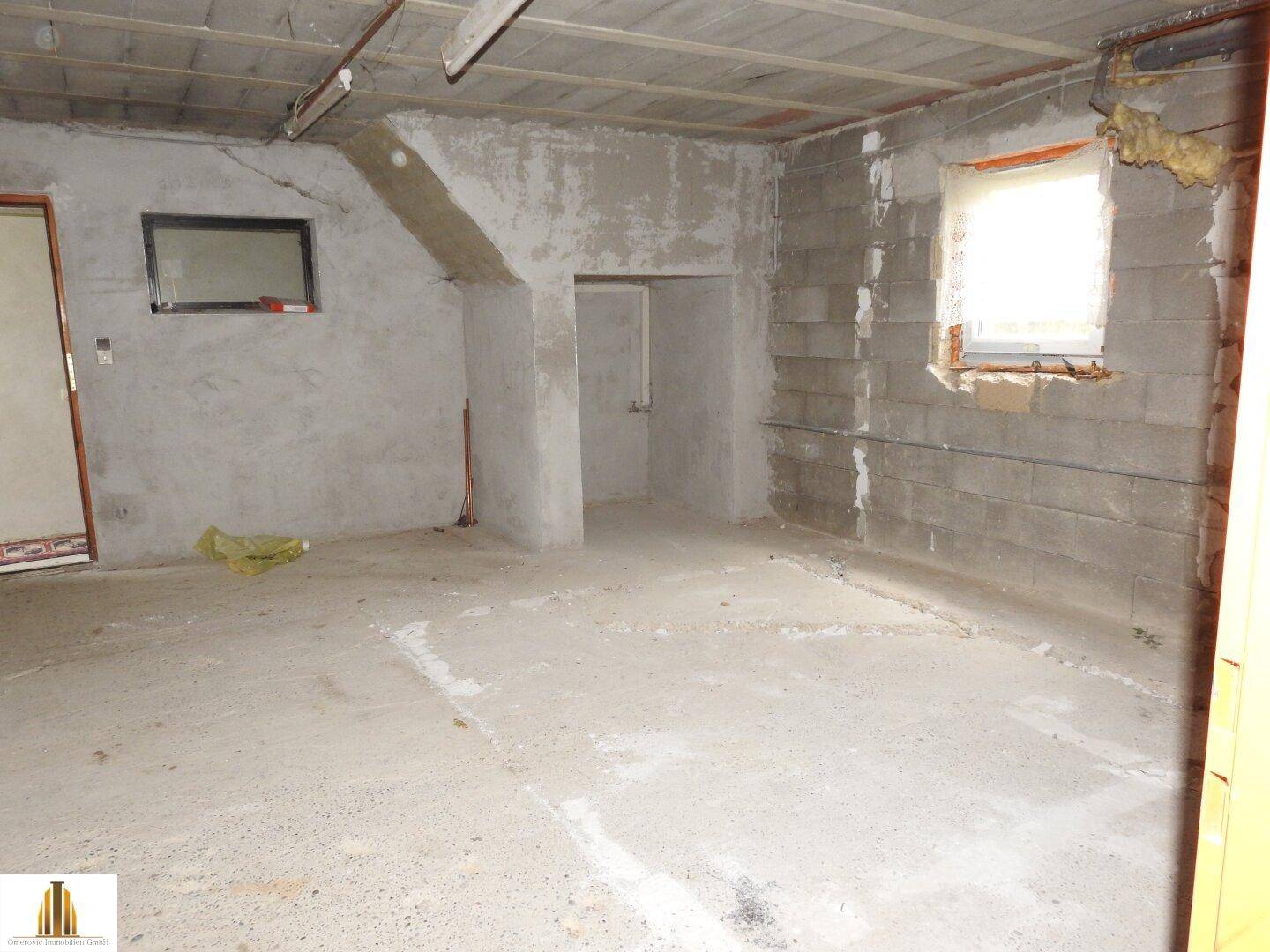Großer, unausgebauter Kellerraum mit Betonboden und Wänden, bereit für Renovierung.