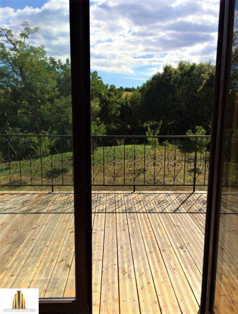 Blick von der Holzterrasse durch die Terrassentür auf die umliegende Natur.