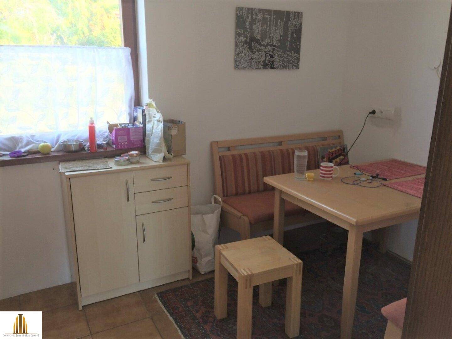 Küchenbereich mit Esstisch, Sitzgelegenheiten und einem Fenster für natürliches Licht.