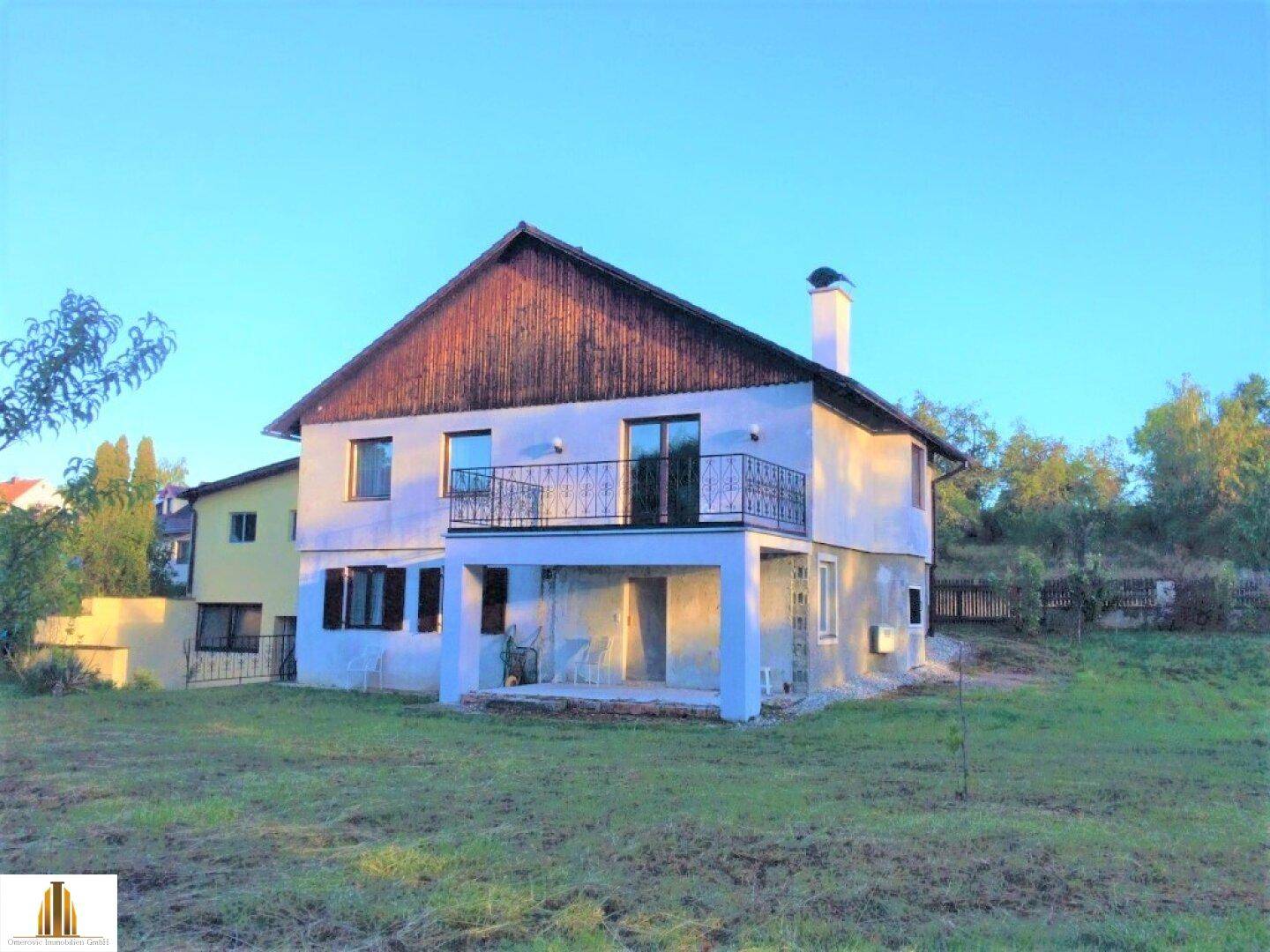 Rückansicht des Hauses mit Balkon und Blick auf den weitläufigen Gartenbereich.