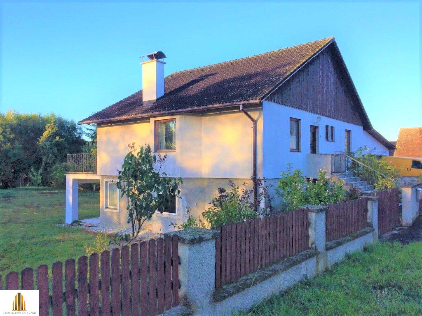 Ansicht des Hauses von der Seite mit Garten und einem kleinen Balkon im oberen Stockwerk.