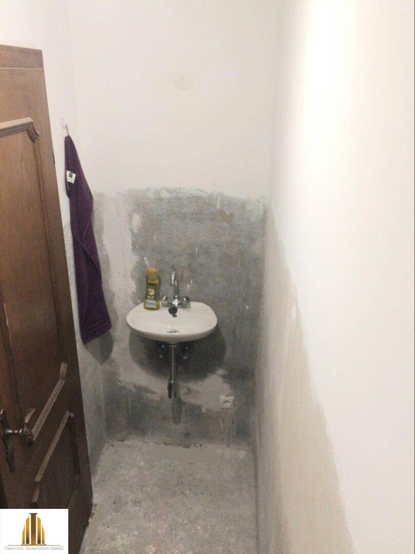 Kleines WC mit Waschbecken und unfertigen Wänden, ideal für eine Renovierung.