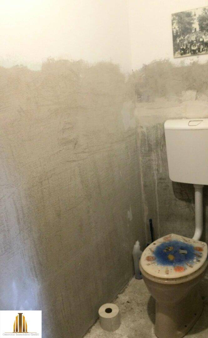 Toilette mit unfertigen Wänden und einfacher Ausstattung, benötigt Renovierung.