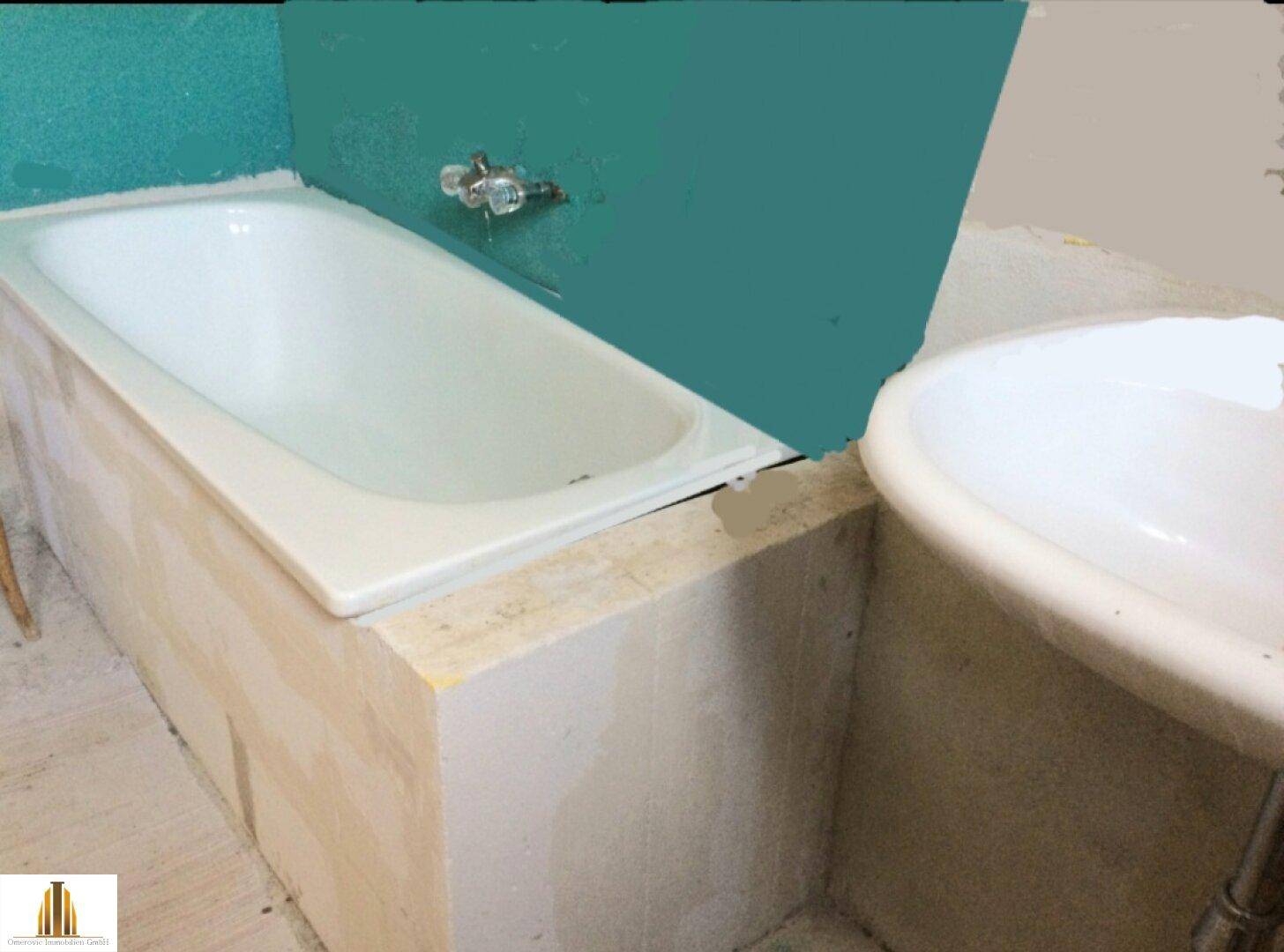 Badezimmer im Rohbau mit Badewanne und Waschbecken, bereit für die Fertigstellung.