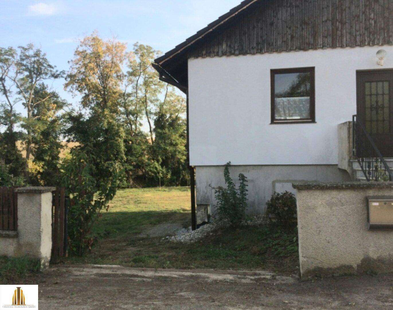 Seitenansicht eines Hauses mit Zugang zum Garten und umgebender Natur.