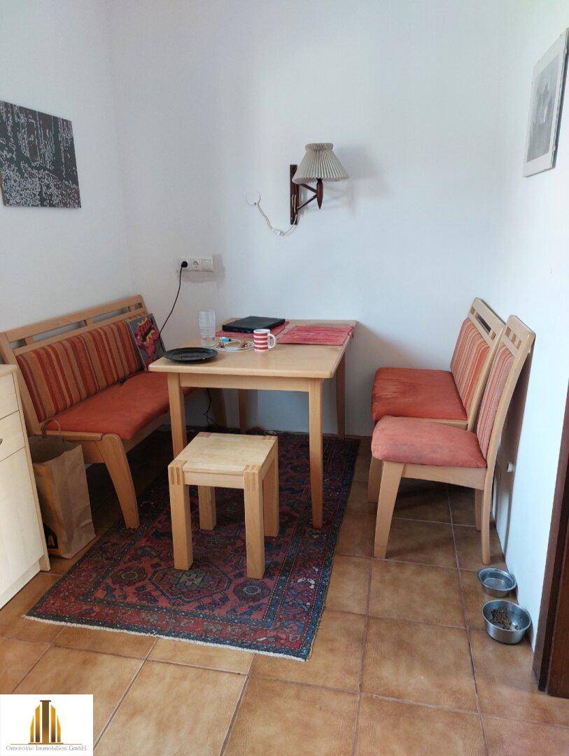 Essbereich in der Küche mit Holztisch, Bänken und Fliesenboden.