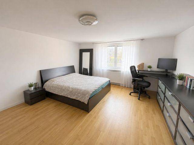 Modernes Schlafzimmer mit Doppelbett, Schreibtisch und großem Fenster.