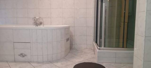 Badezimmer mit weiß gefliesten Wänden, Badewanne und separater Duschkabine.