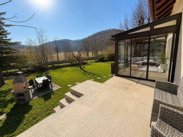 Große Sonnenterrasse mit Grillplatz, Gartenmöbeln und Blick auf die Landschaft.