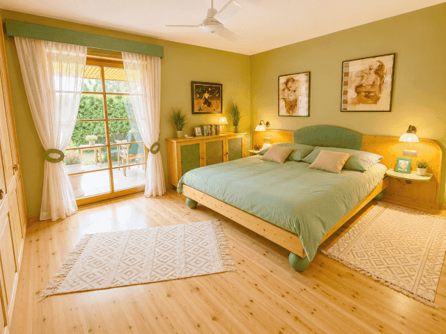 Helles Schlafzimmer mit Holzboden, Doppelbett und direktem Zugang zur Terrasse, mit Deckenventilator.