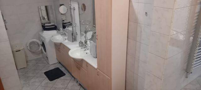 Geräumiges Badezimmer mit Doppelwaschbecken, Spiegelschrank und Waschmaschine.