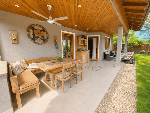 Geräumige überdachte Terrasse mit Essbereich, Deckenventilator und Blick in den grünen Garten.
