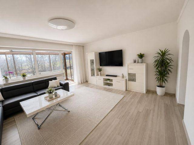 Geräumiges Wohnzimmer mit modernem Sofa, TV-Möbel und hellem Boden.