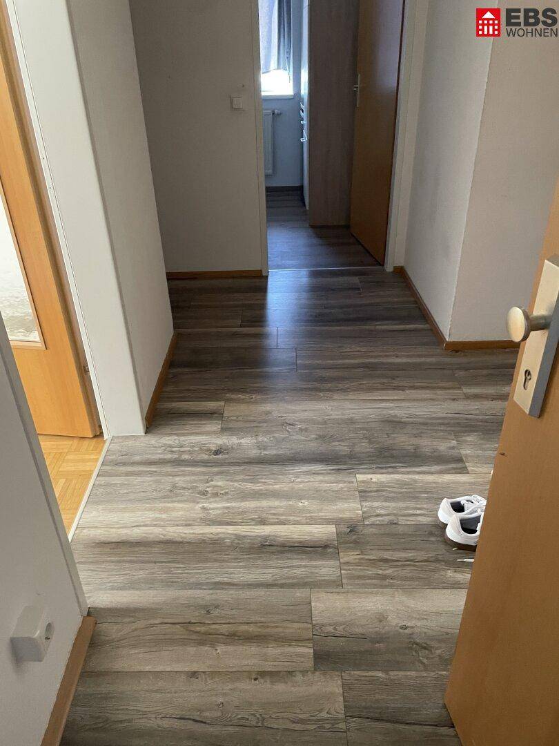 Heller Flur mit modernem Laminatboden in Holzoptik, der zu den angrenzenden Räumen führt.