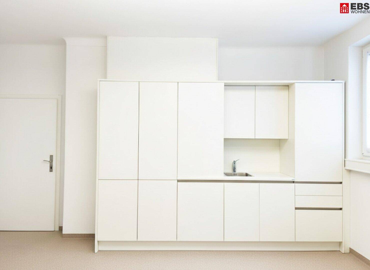 Kompakte, weiße Küchenzeile mit Spüle und viel Stauraum in minimalistischem Design.