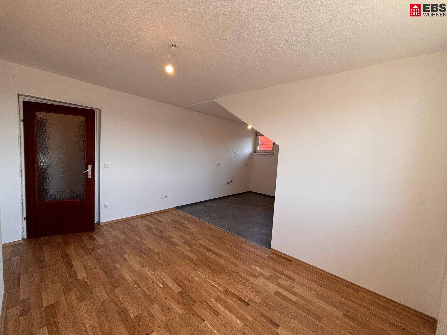 Geräumiges Zimmer mit Holzboden und Dachschräge, ideal für individuelle Gestaltung.