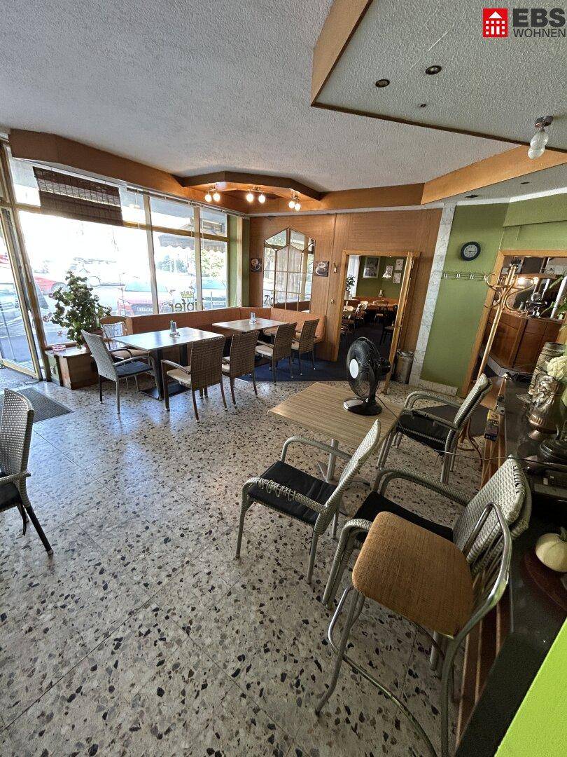 Heller Café-Innenraum mit Terrazzo-Boden, verschiedenen Sitzgelegenheiten und Blick nach draußen.