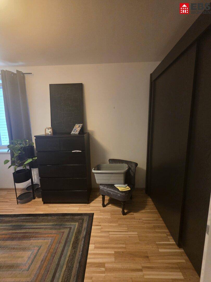 Schlafzimmerbereich mit dunklem Kleiderschrank und Holzboden.