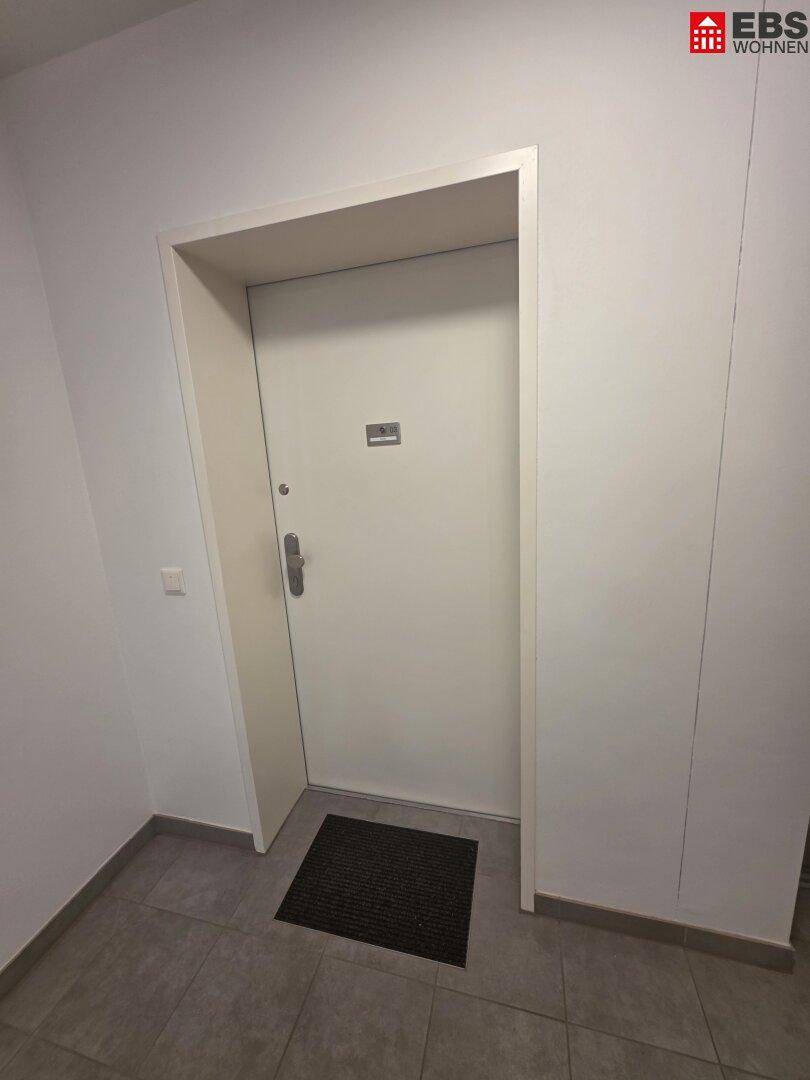 Eingangsbereich mit weißer Wohnungstür und Fliesenboden.