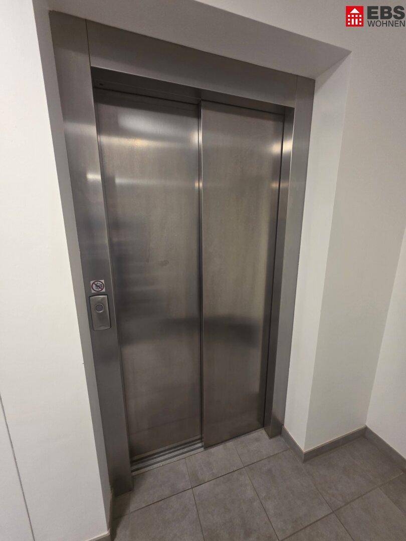 Moderner Aufzug mit Edelstahltüren in einem Mehrfamilienhaus.