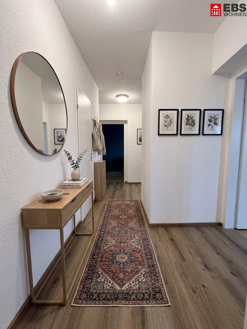 Heller Flur mit Laminatboden, Spiegel und dekorativer Konsole.