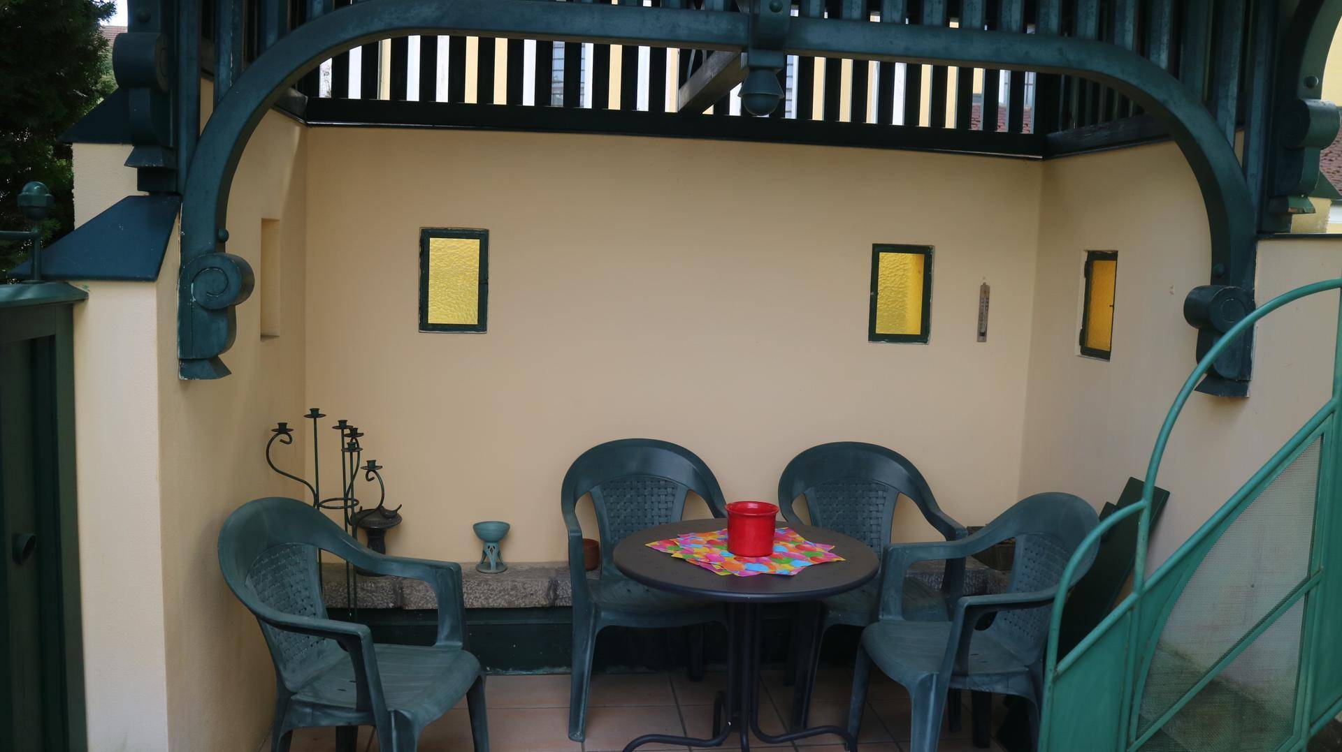 Gemütlicher Außenbereich unter einer Holzpergola mit Plastikmöbeln, ideal für entspannte Stunden.