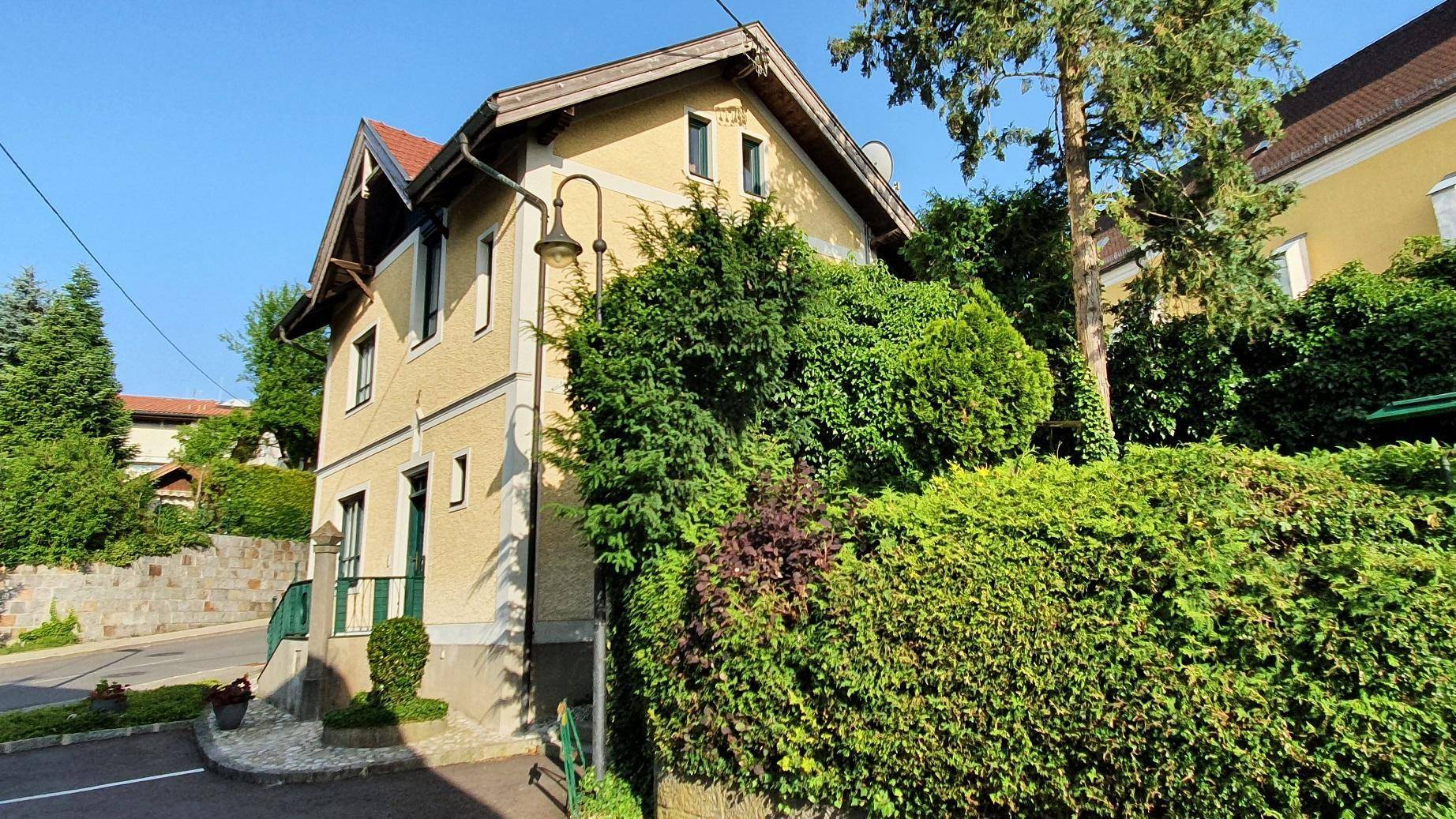 Charmantes Haus mit üppiger grüner Bepflanzung und traditioneller Architektur in sonniger Lage.