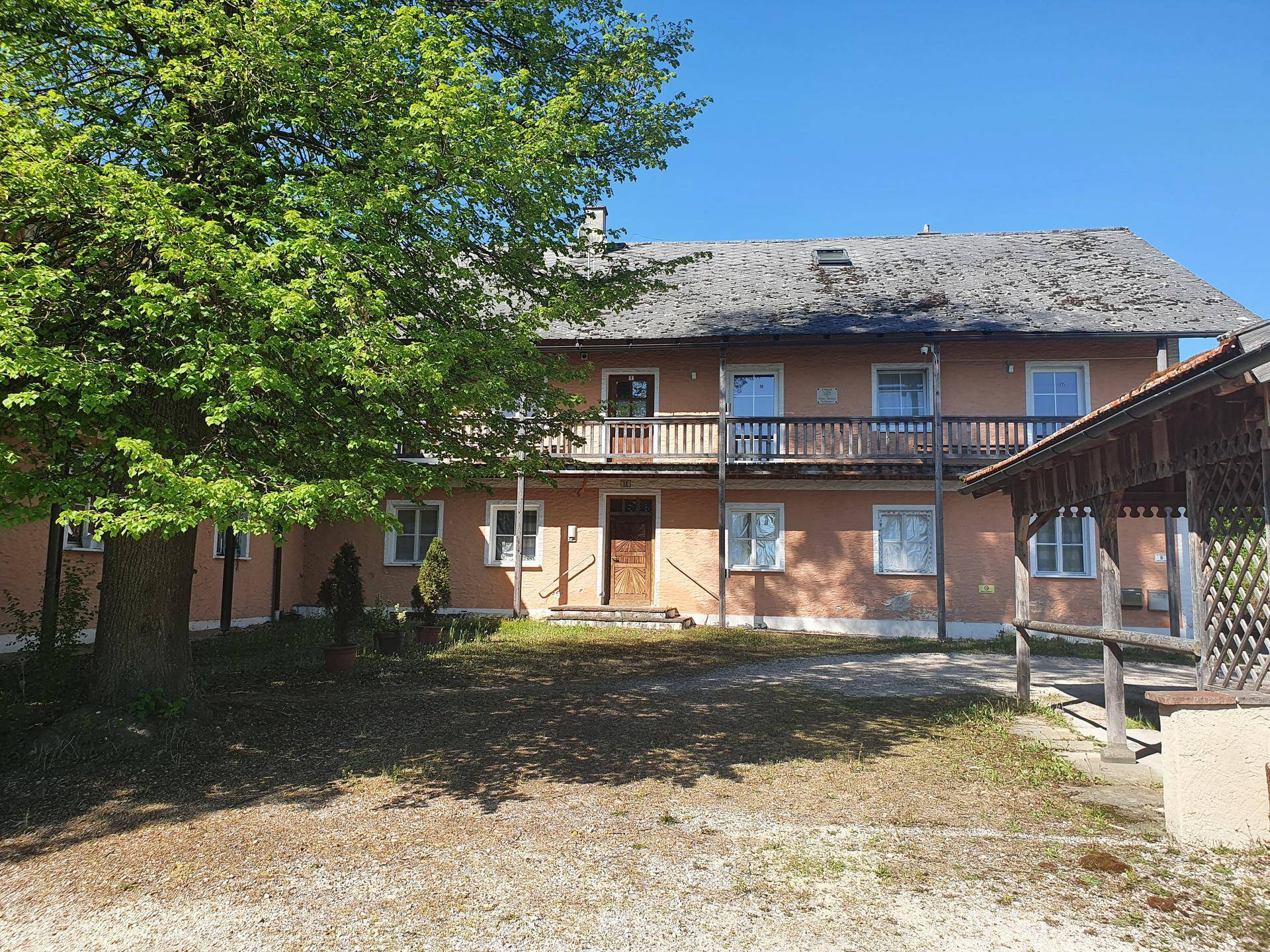 Historisches Wohnhaus mit traditioneller Architektur, Holzbalkonen und großem Vorplatz.