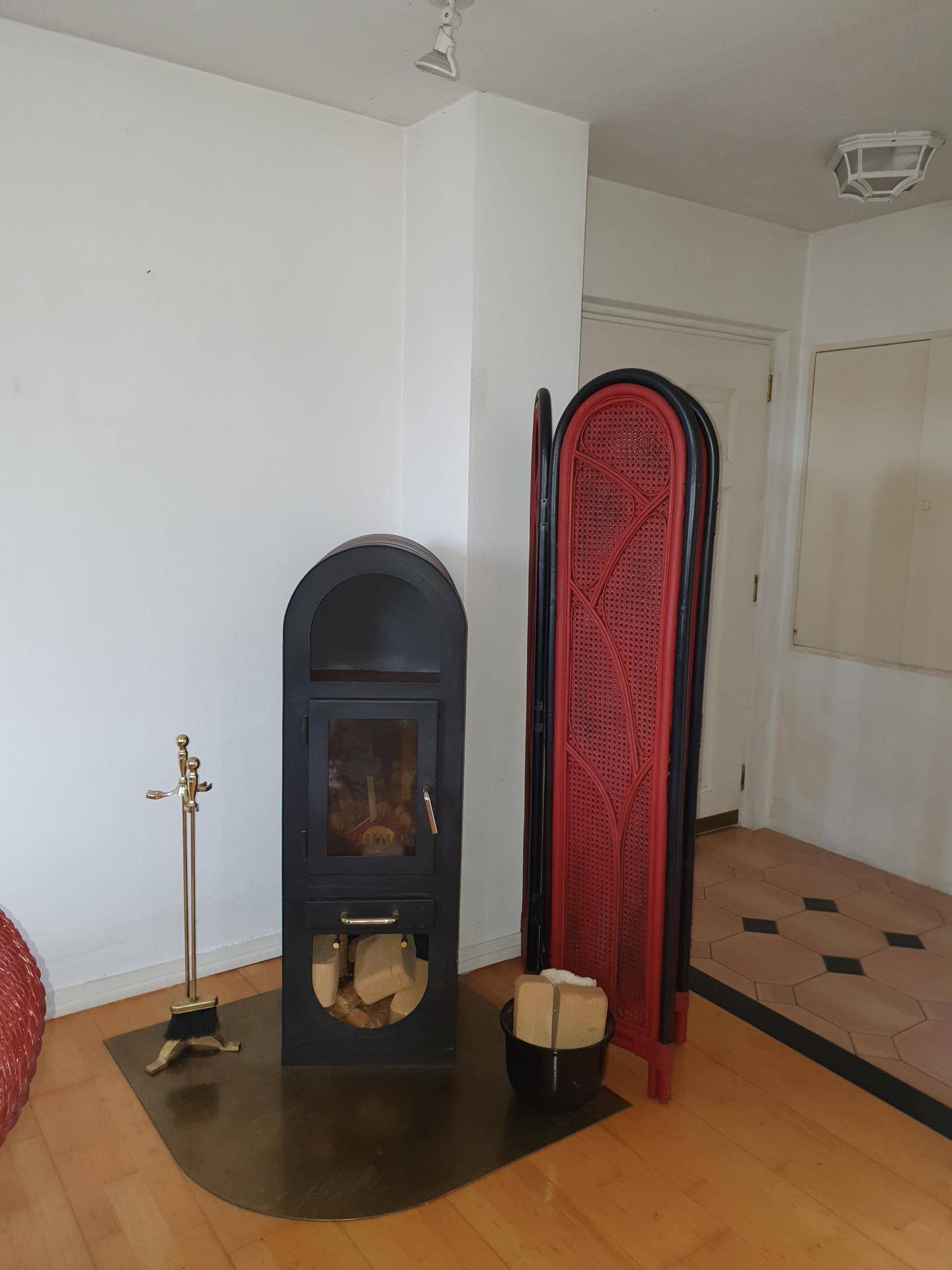 Moderner Holzofen mit Brennholz und dekorativem Raumteiler, schafft eine gemütliche Atmosphäre.