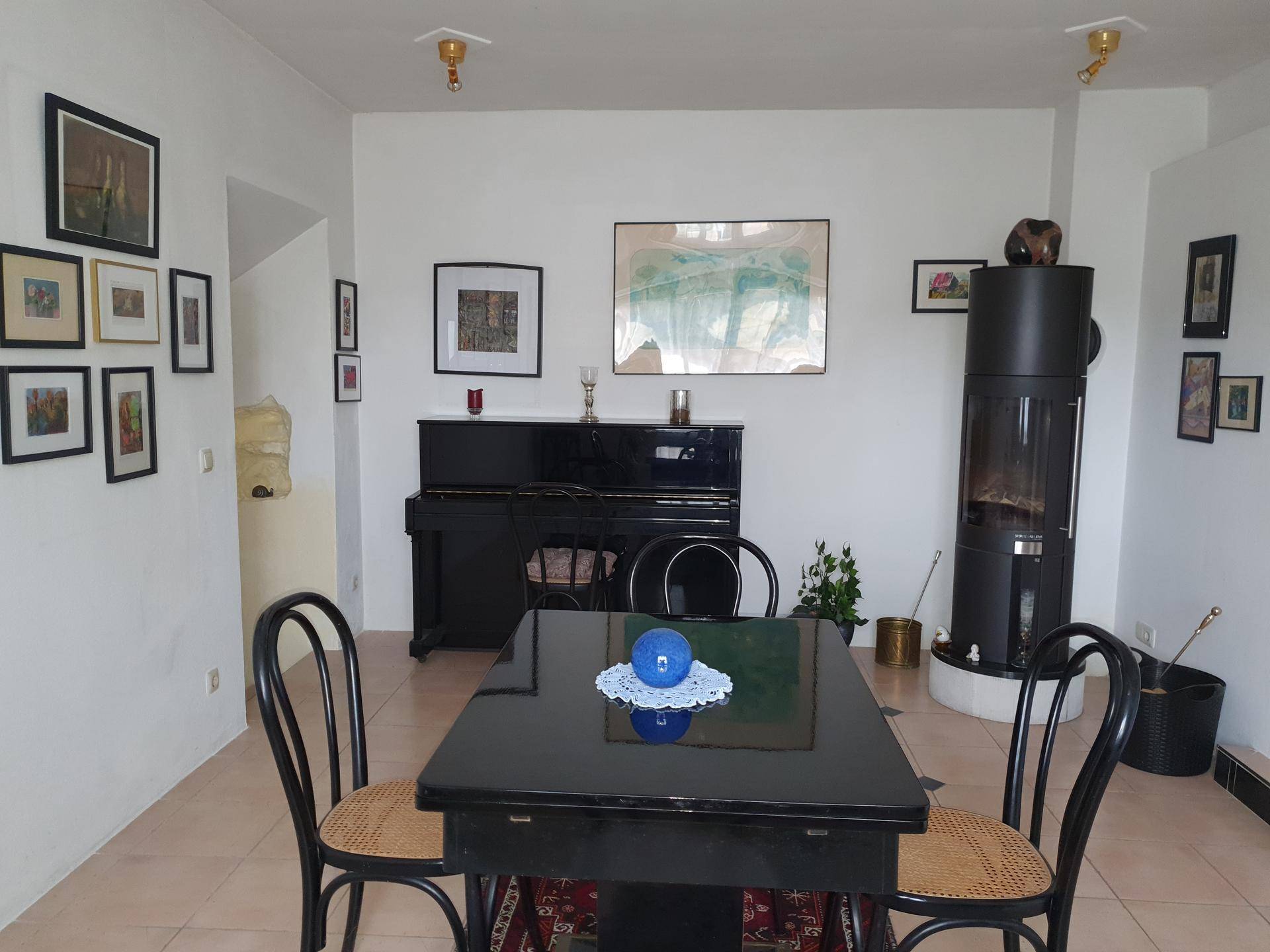 Geräumiger Essbereich mit Klavier, Esstisch und modernem Kaminofen, ideal für gesellige Runden.