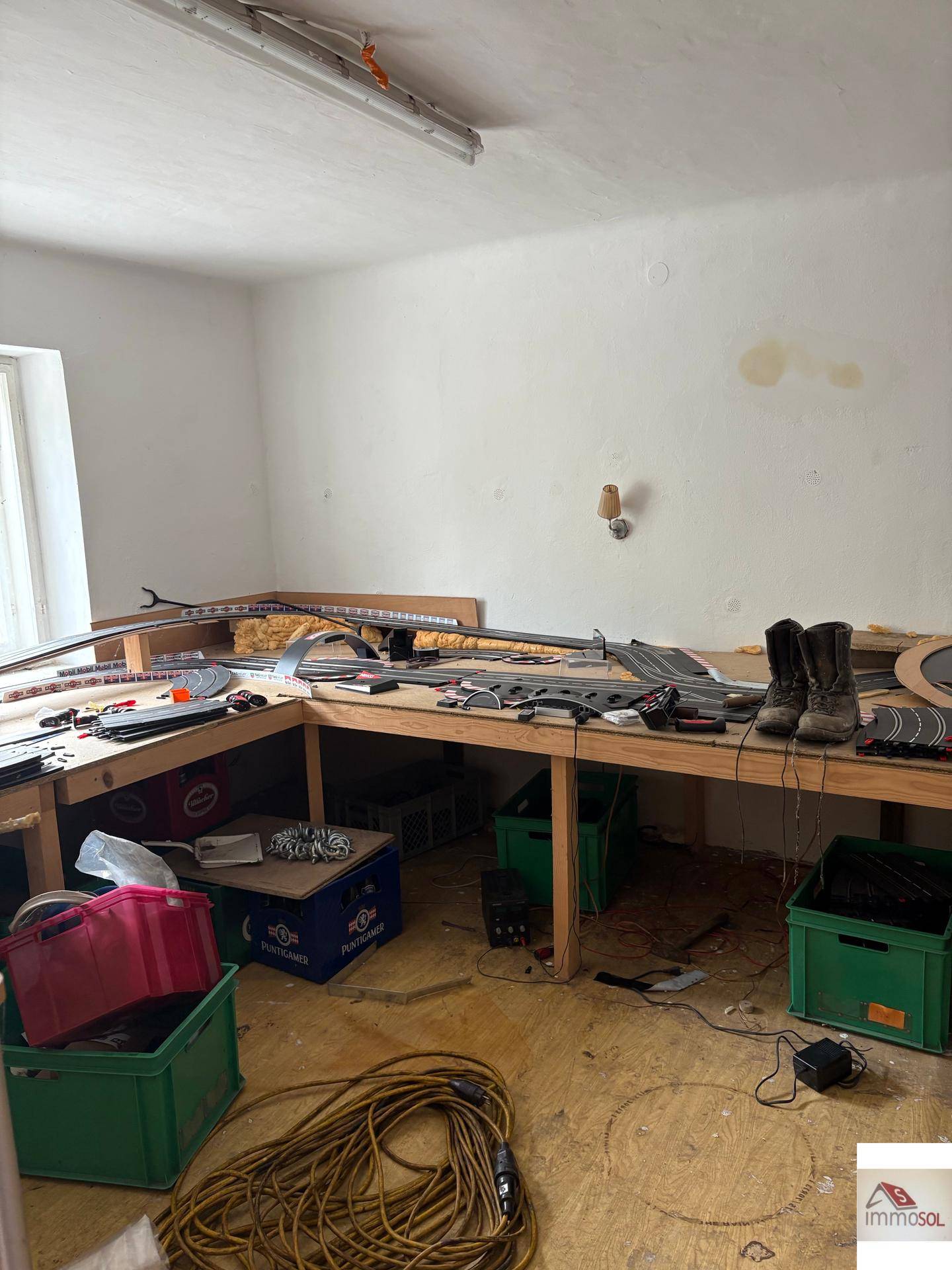 Werkstattraum mit einer großen Arbeitsfläche, Werkzeugen und Kabeln, bereit für handwerkliche Tätigkeiten.