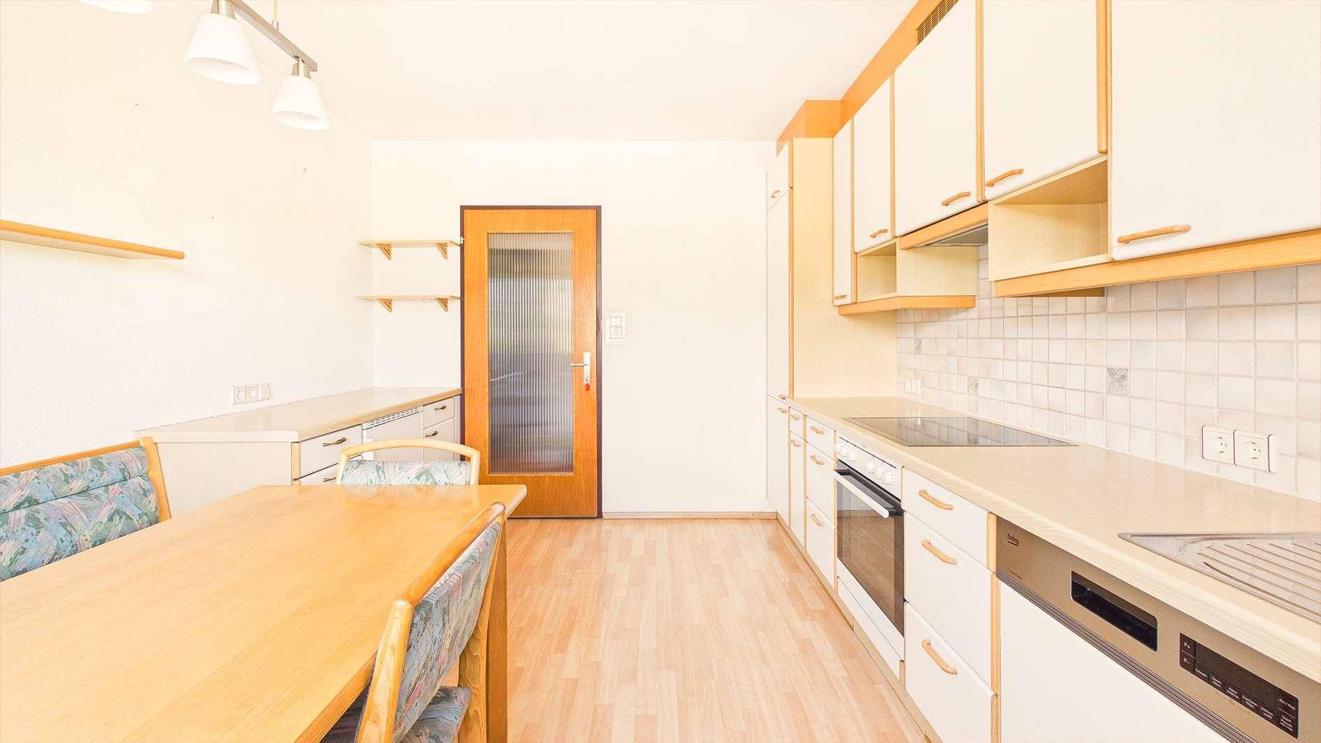 Geräumige Küche mit Essecke, Einbauküche und Holztür mit Glaseinsatz.