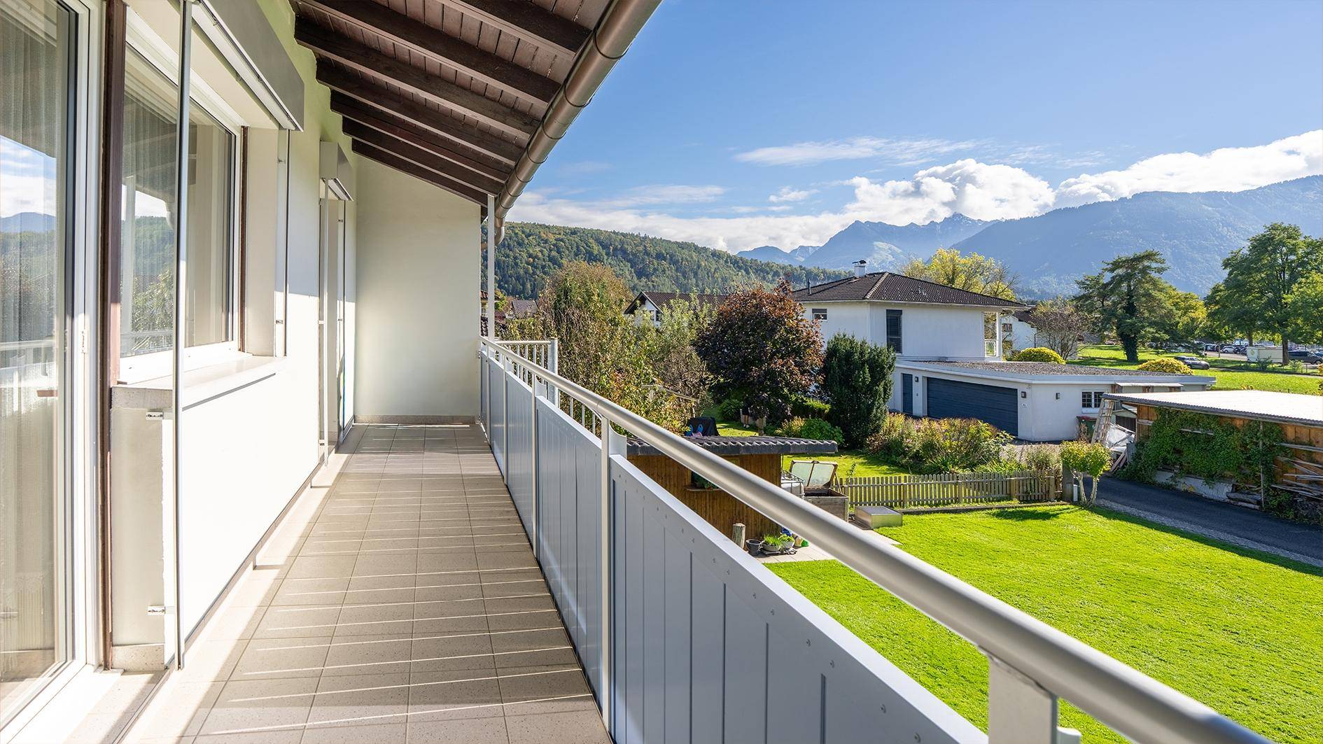 Langer Balkon mit Fliesenboden und weitem Blick auf die Berge und die Umgebung.