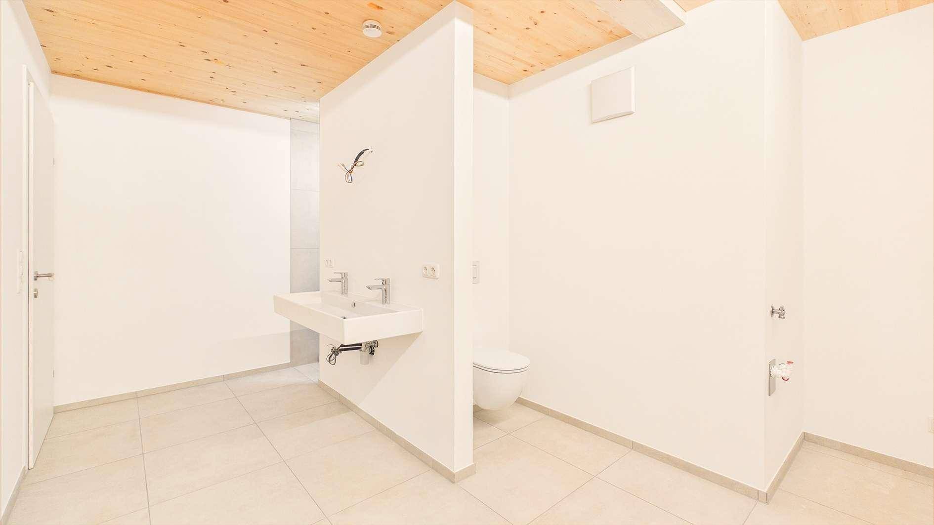 Modernes Badezimmer mit Wand-WC, schwebendem Waschbecken und hellen Fliesen.