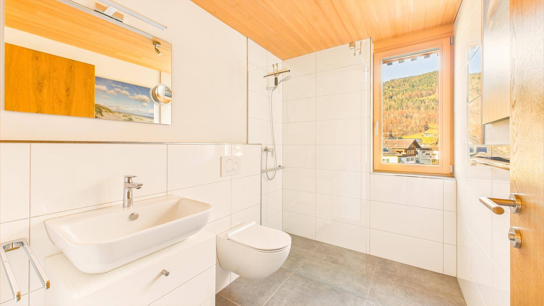 Modernes Badezimmer mit Dusche, WC, Waschbecken und Fenster mit Bergblick.