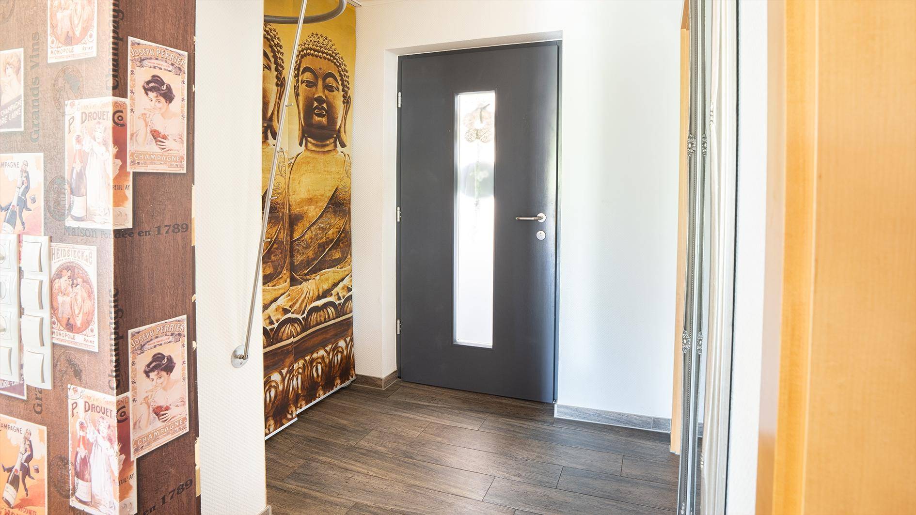 Heller Flur mit Holzboden und einer modernen Eingangstür mit Glaseinsatz.