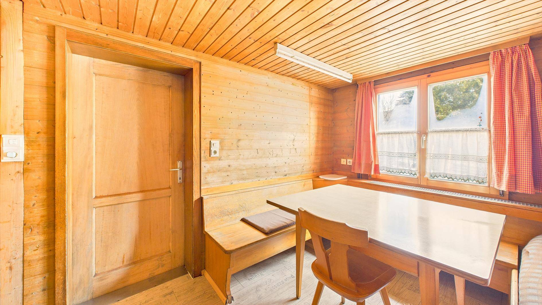 Traditioneller Essbereich mit Holztäfelung, eingebauter Sitzbank und Esstisch am Fenster.