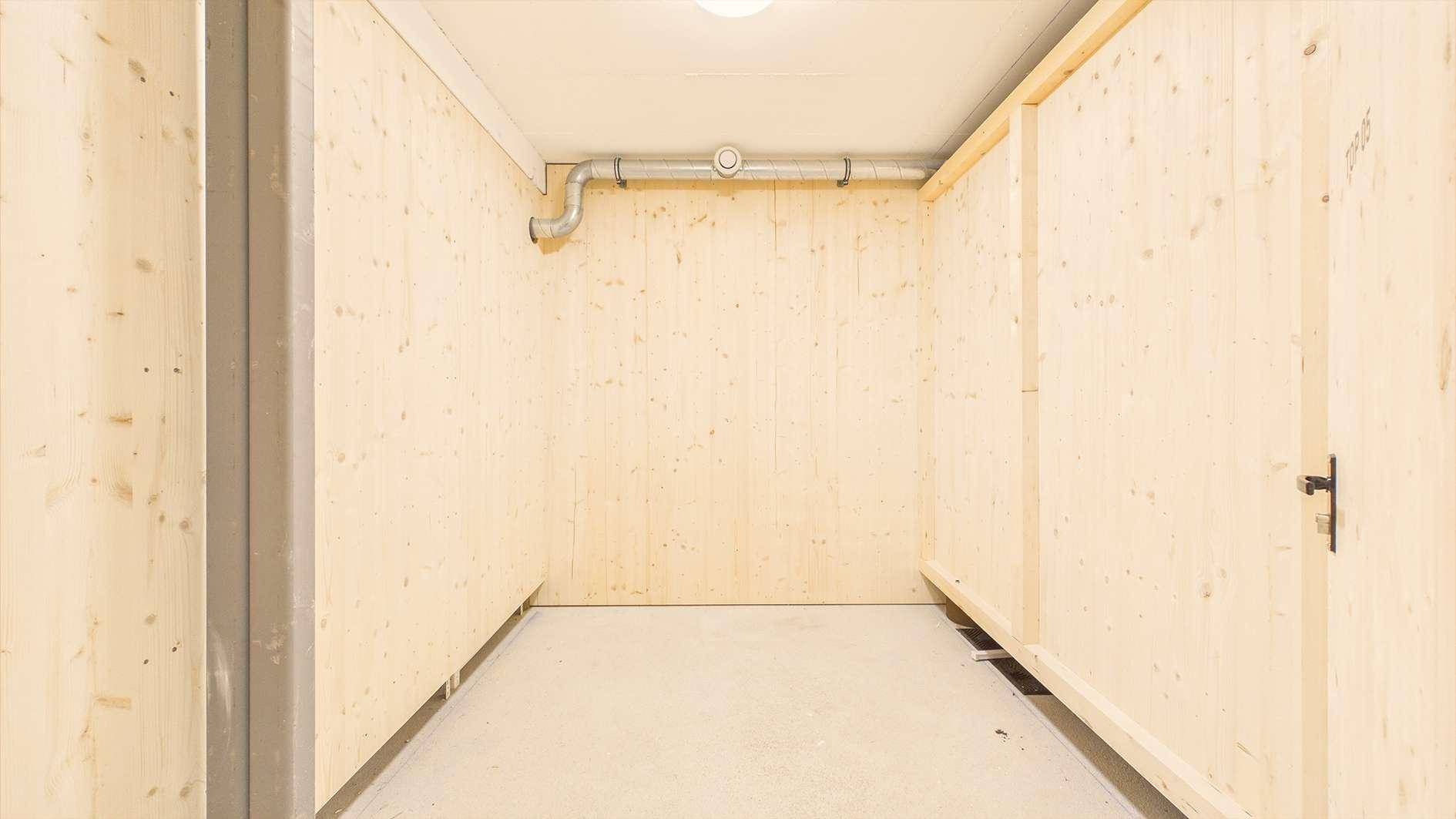 Geräumiger Kellerraum mit Holzwänden und Betonboden, ideal als Abstellfläche.