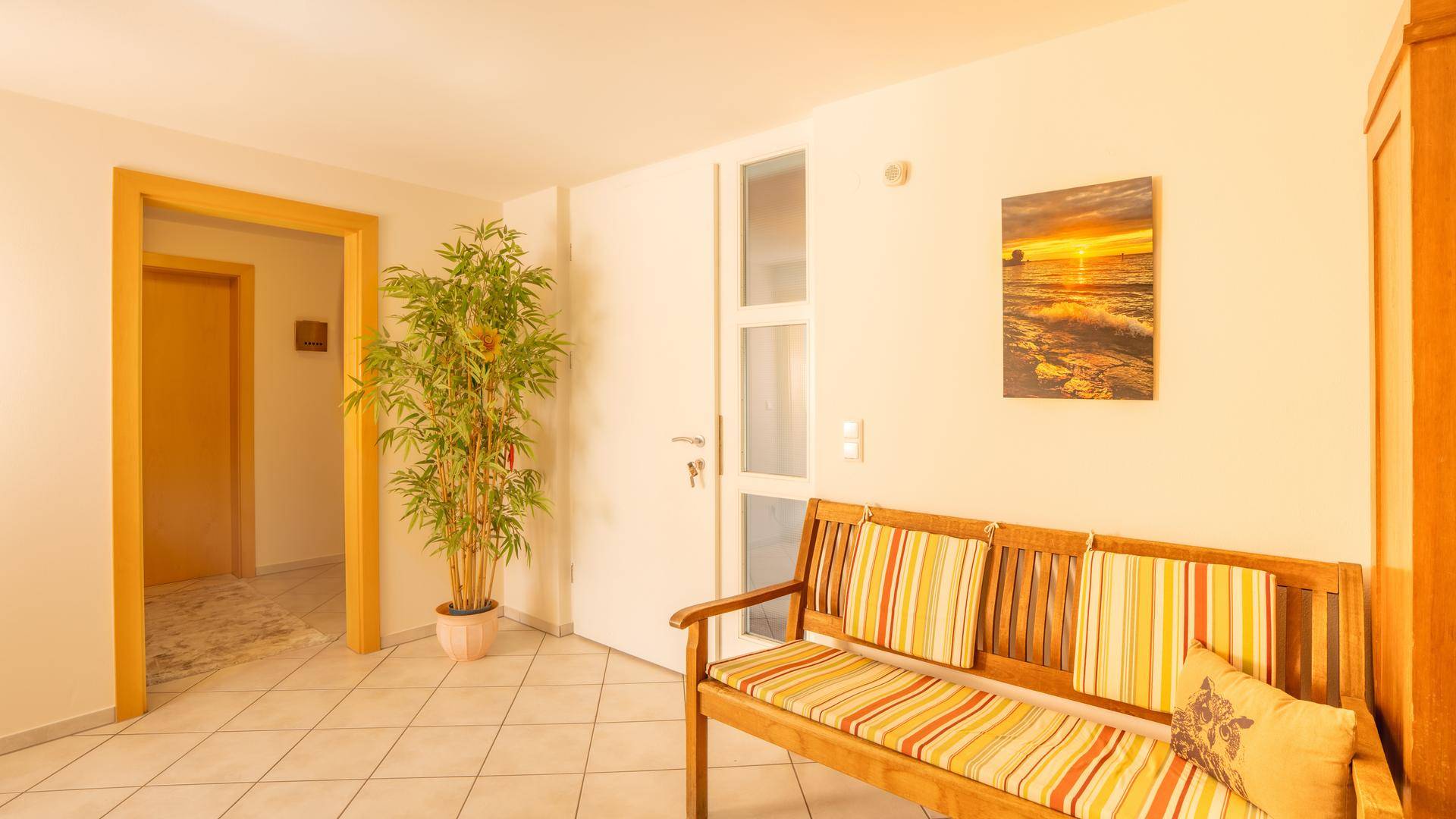 Heller Eingangsbereich mit Sitzbank, Fliesenboden und dekorativer Pflanze für einladende Atmosphäre.