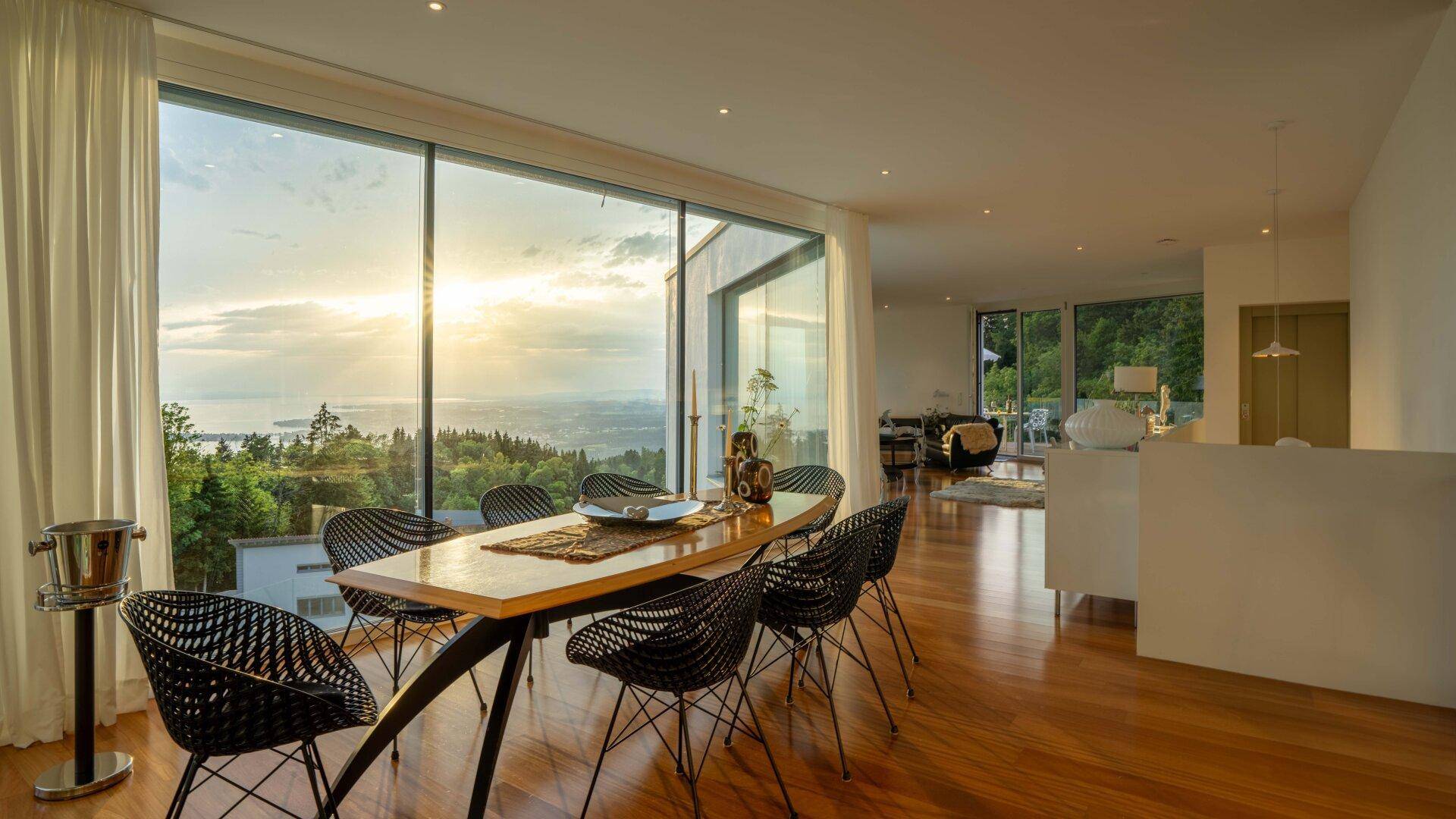 Heller Essbereich mit Holzboden, modernen Stühlen und Panoramafenstern mit weitem Blick.