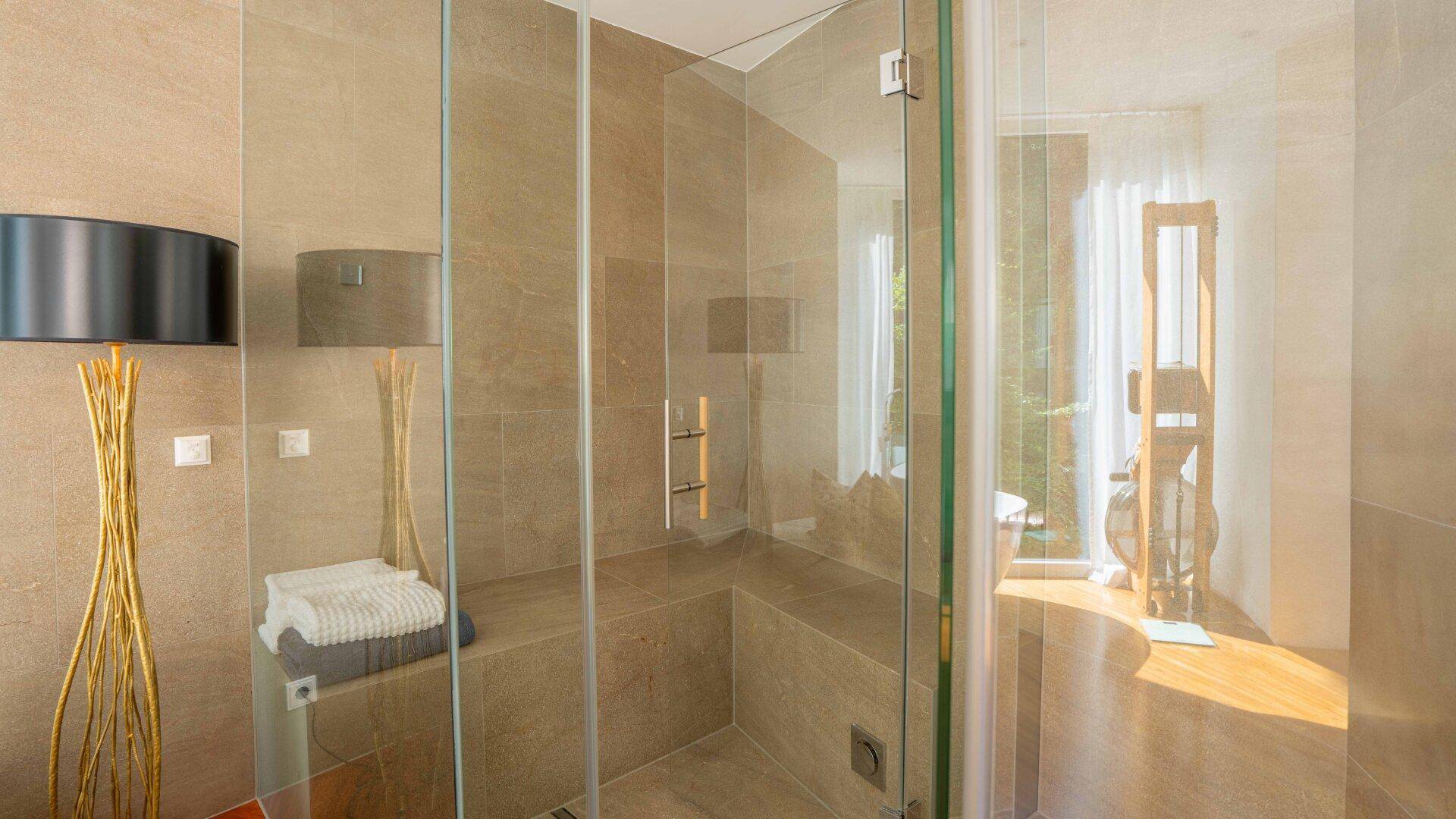 Geräumige, moderne begehbare Dusche mit Glaswänden und großformatigen Fliesen im Badezimmer.